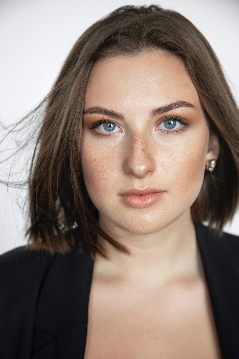 A zoomed image of a woman staring with grey eyes and a short hair.